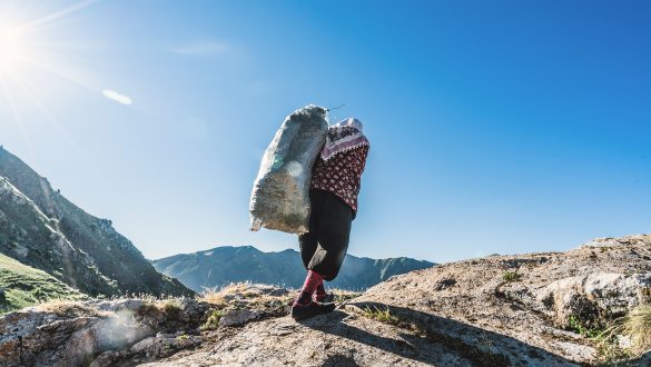 Woman carrying a bag of fresh cut grass up a steep hill